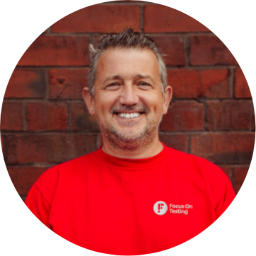 Photo of Hadrian smiling and wearing the red Focus On Testing uniform 