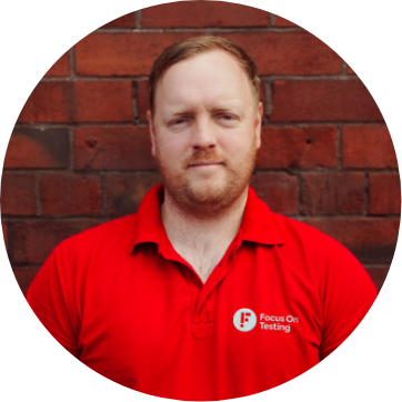 Photo of Michael smiling and wearing the red Focus On Testing uniform 