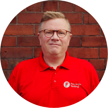Photo of Richard smiling and wearing the red Focus On Testing uniform 